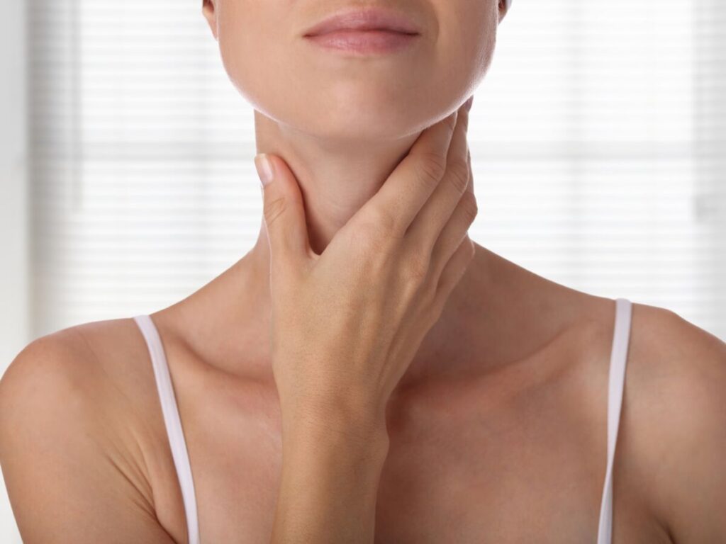 Femme examinant sa thyroïde, maladie de Basedow et ses symptômes visibles