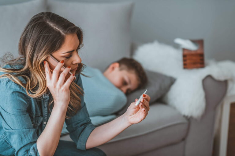 Jeune femme allongée sous une couverture buvant une tisane pour faire baisser la fièvre naturellement
