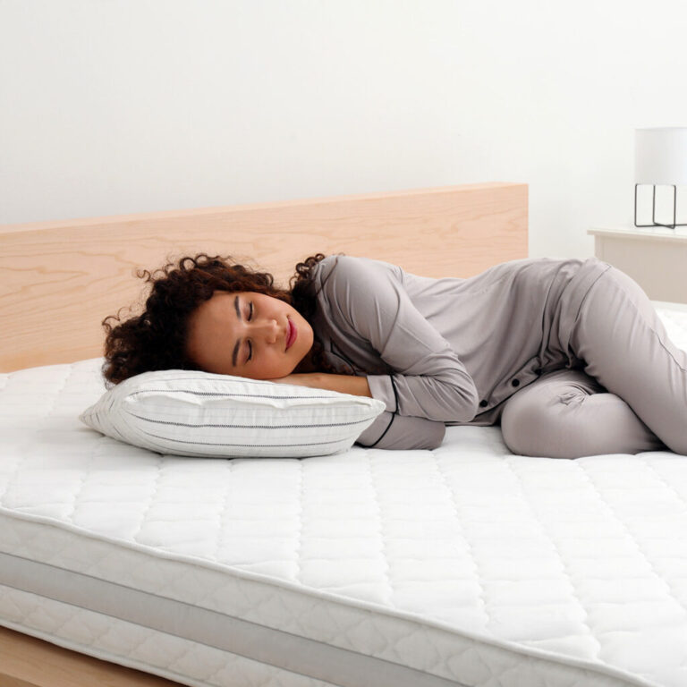 Jeune femme testant un matelas en magasin, idéale pour illustrer le choix d’un matelas selon le poids